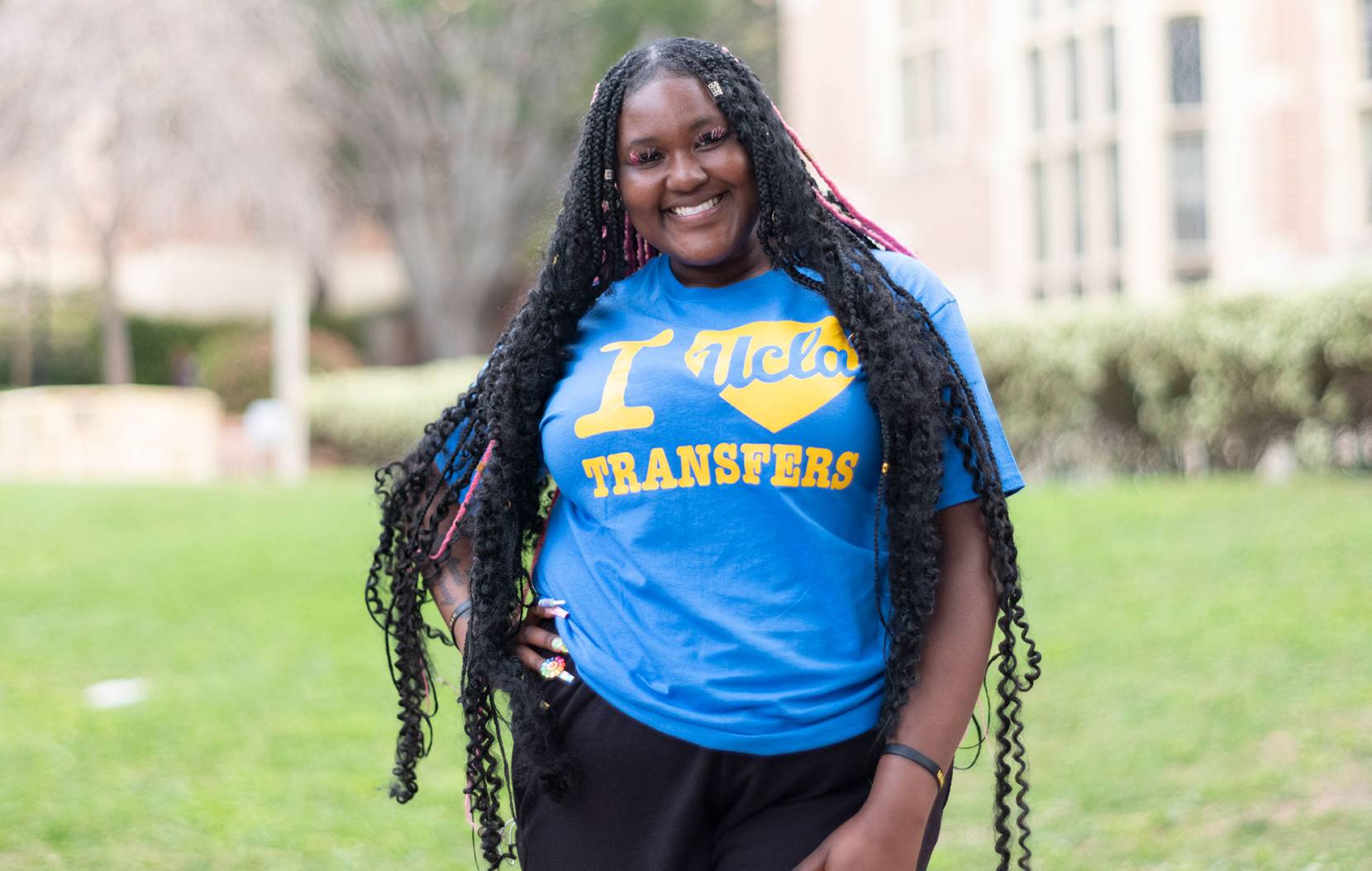 Student posing in a blue tshirt that says "I love UCLA transfers"